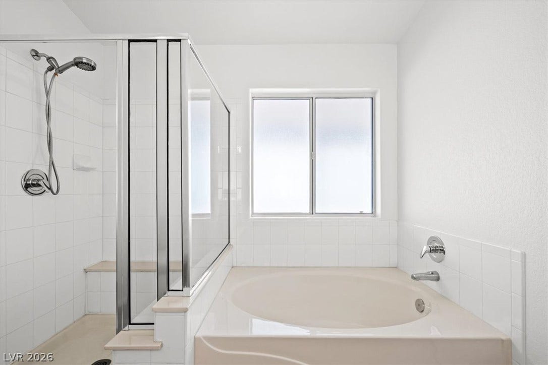 3535 Barrel Bronco Court, North Las Vegas, NV 89032 Tiled finishes and a frosted window frame the relaxing soaking tub and separate shower.