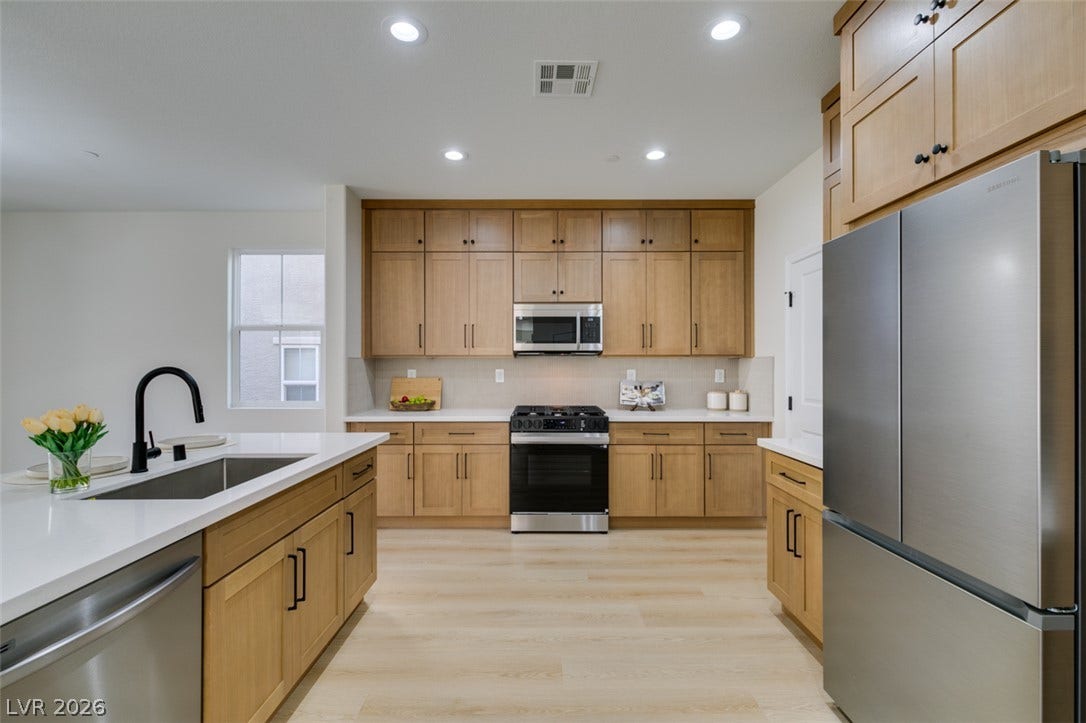 197 Sicily Hills Court, Henderson, NV 89012 Gleaming stone countertops and warm wood cabinetry define this modern open kitchen layout.