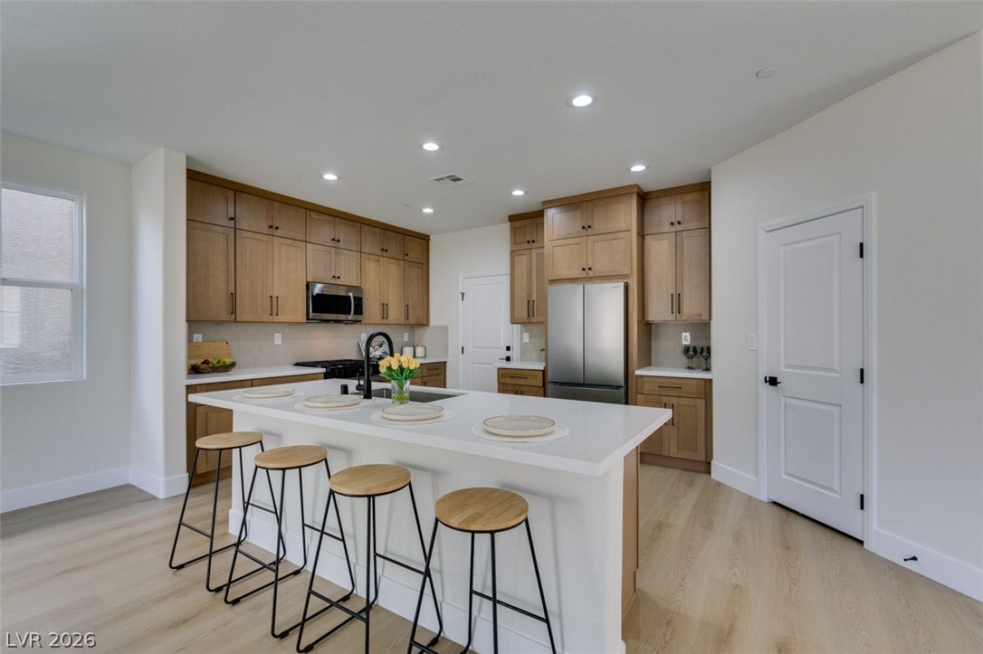 197 Sicily Hills Court, Henderson, NV 89012 Recessed lighting illuminates this modern culinary space featuring flat-panel wood cabinetry and clean quartz countertops.
