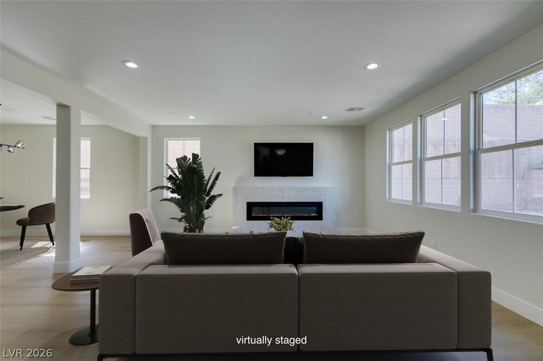 197 Sicily Hills Court, Henderson, NV 89012 An elegant modern fireplace anchors this airy living space complete with light wood flooring.