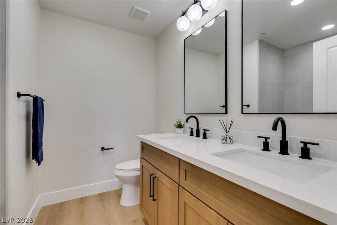 197 Sicily Hills Court, Henderson, NV 89012 A contemporary dual vanity with stone countertops highlights this sleek bathroom space.