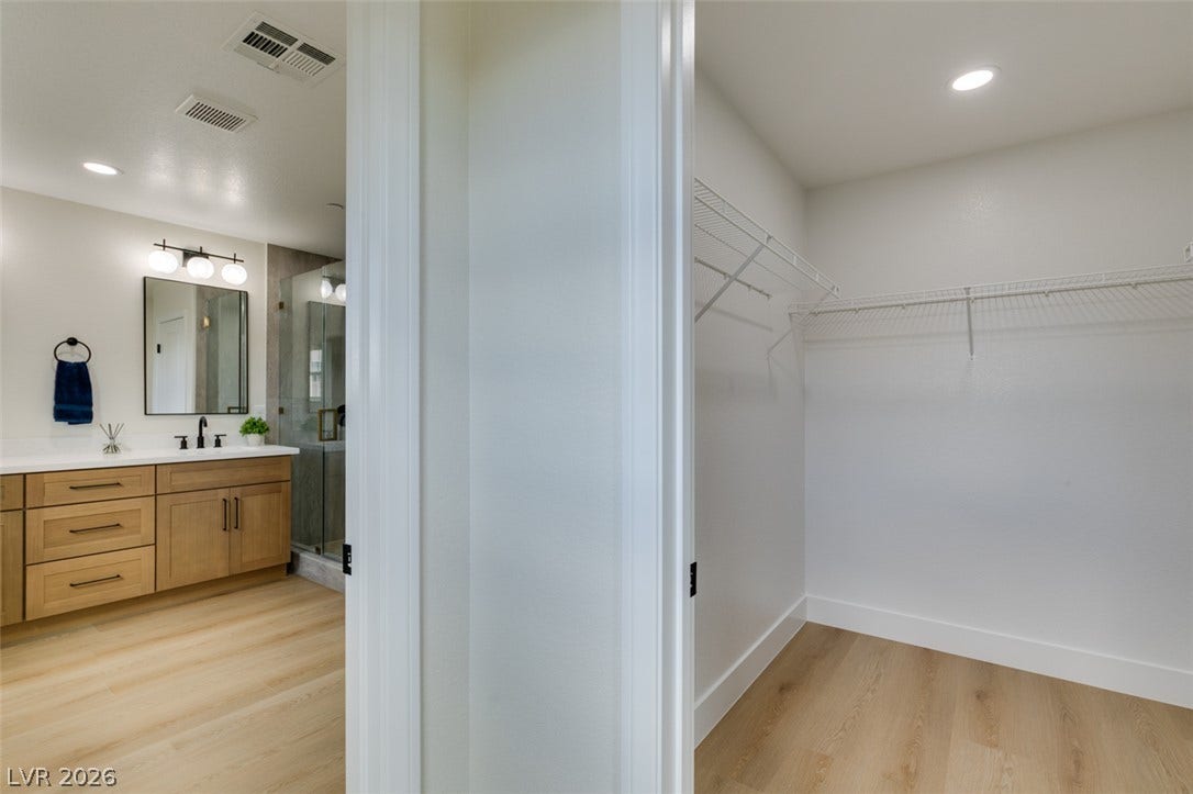 197 Sicily Hills Court, Henderson, NV 89012 A spacious walk-in closet stands adjacent to a modern bathroom with light wood flooring.