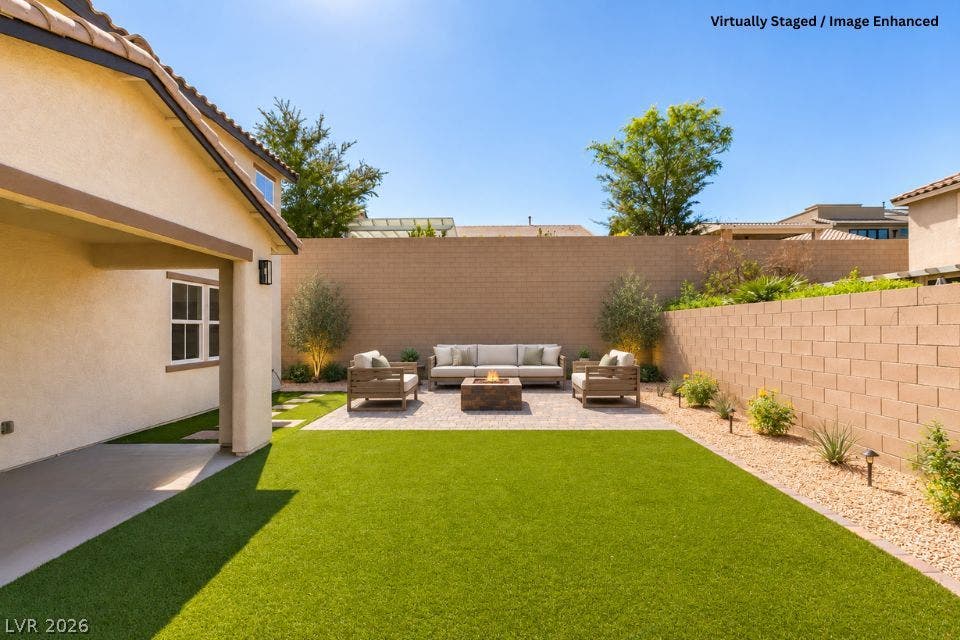 197 Sicily Hills Court, Henderson, NV 89012 An inviting backyard features a manicured lawn, paved patio area, and a stone fire pit.