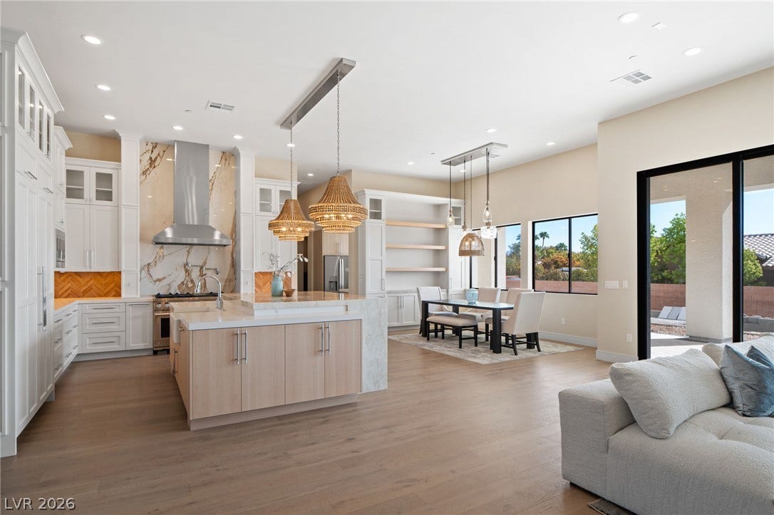 An open floorplan integrates the culinary space with dining and living areas under recessed lighting.