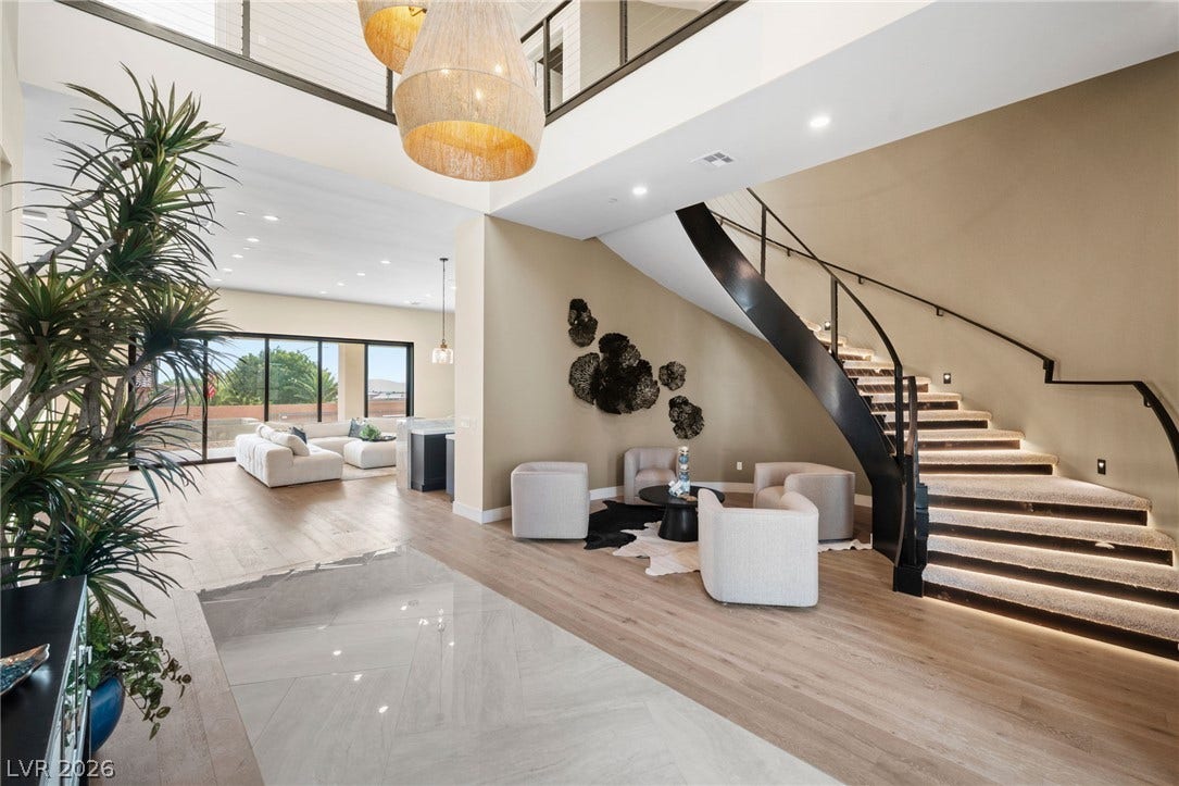 An architectural curved staircase with integrated lighting anchors this grand, open-concept entry foyer.
