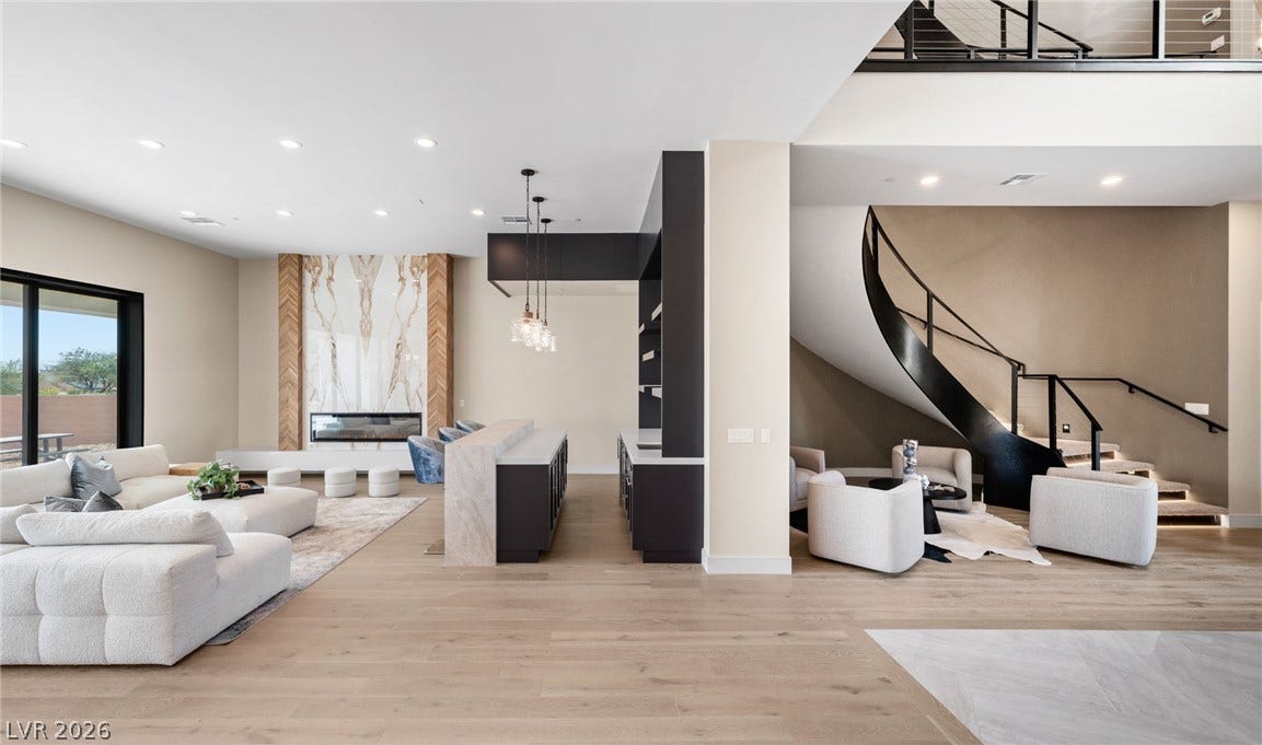 Gleaming hardwood floors and a striking curved staircase anchor this vast, multi-level living pavilion.