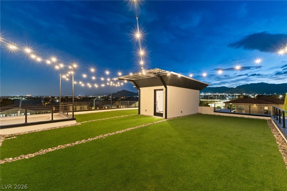 Panoramic mountain and city views unfold from this expansive rooftop terrace under twilight skies.
