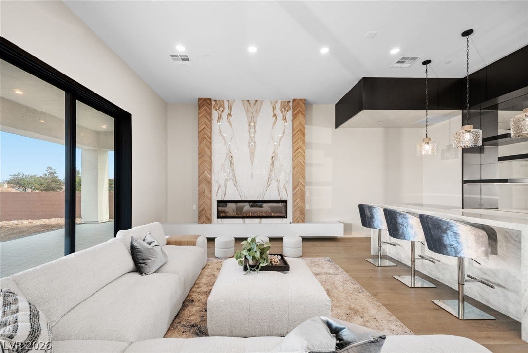 A modern fireplace with bookmatched stone and wood accents anchors the open living space.