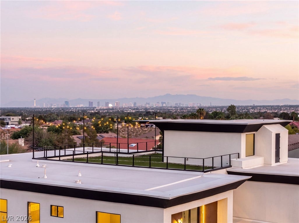 An expansive rooftop deck overlooks a panoramic city skyline and distant mountain ranges.