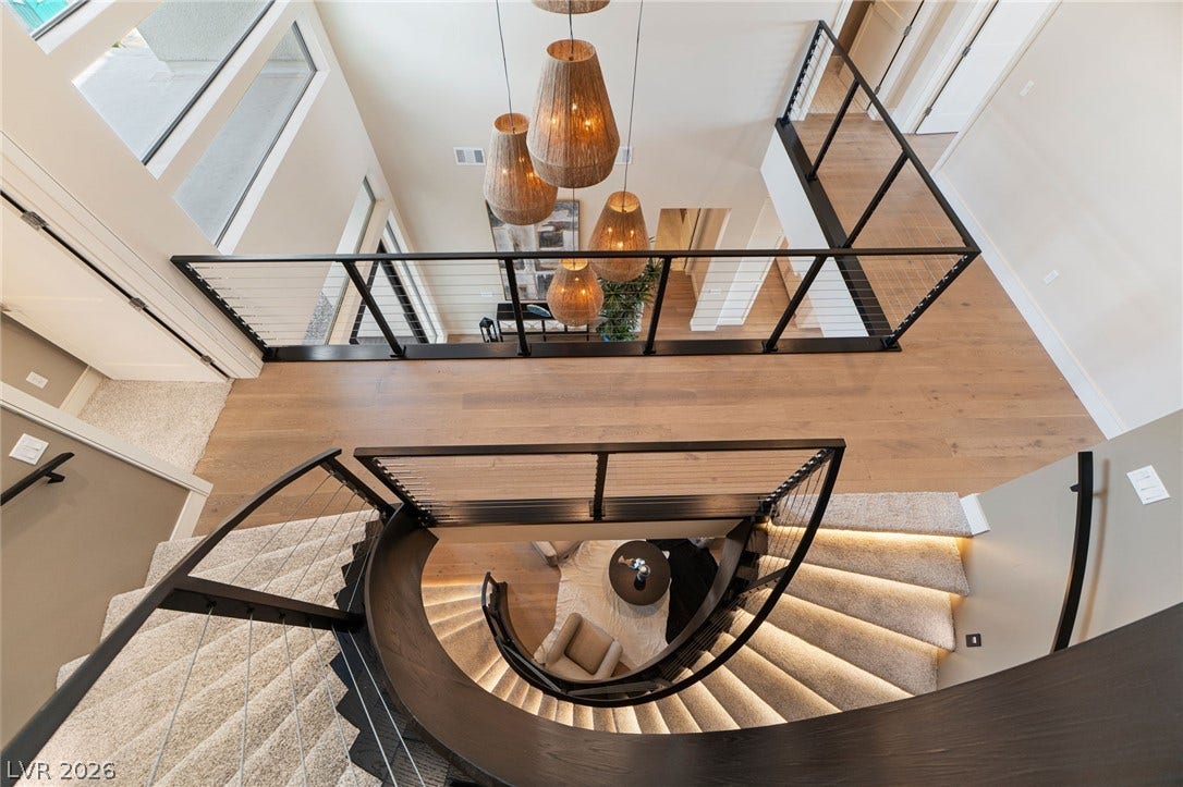 An elegant spiral staircase winds downward from the spacious upper landing featuring warm hardwood flooring.