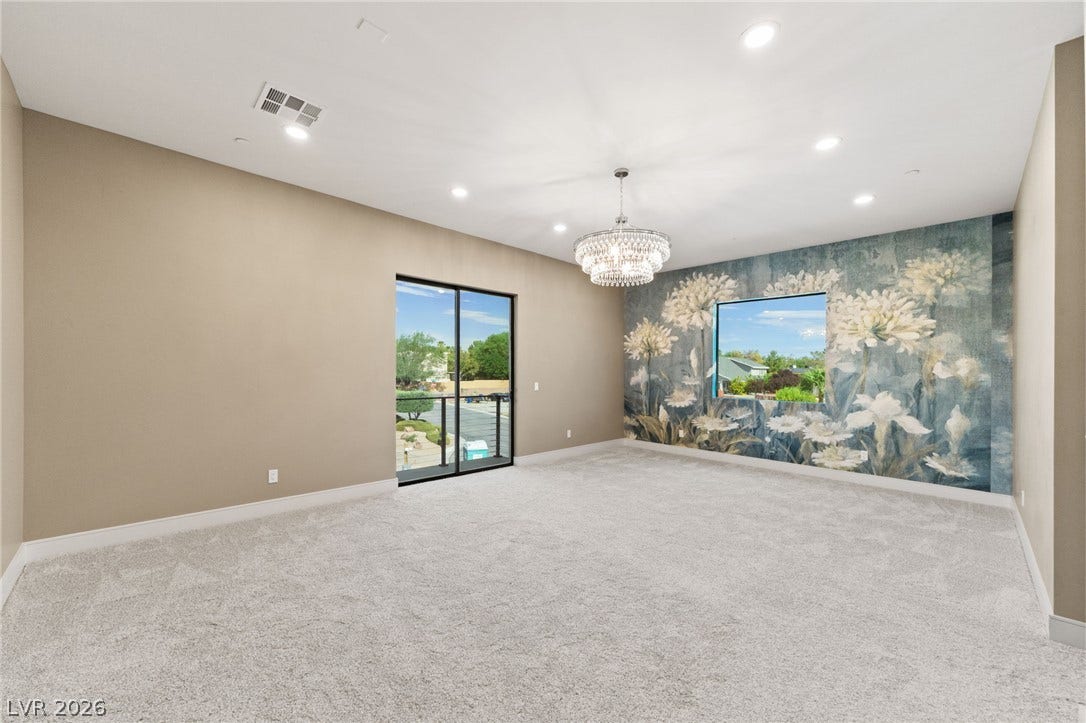 Recessed lights, plush carpeting, and a modern sliding glass door define this airy space.