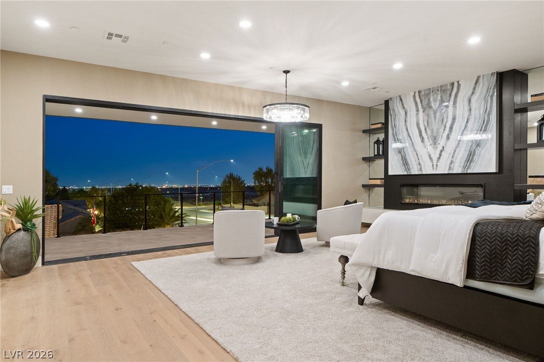 A modern fireplace and wide glass doors opening to city views elevate this bedroom space.
