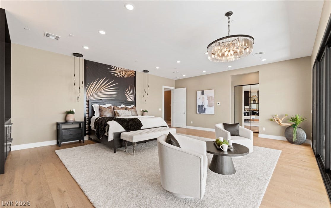 Gleaming wood floors and a crystal chandelier highlight this spacious bedroom retreat.