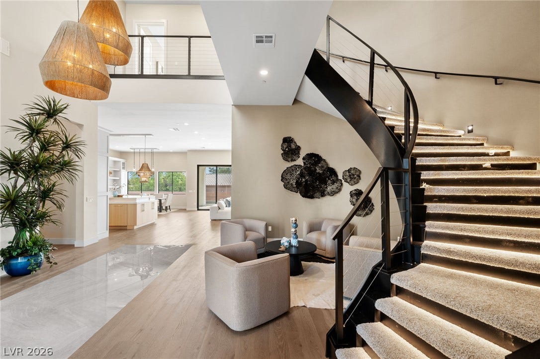 A sweeping staircase with integrated lighting guides the eye through this soaring, open entryway.