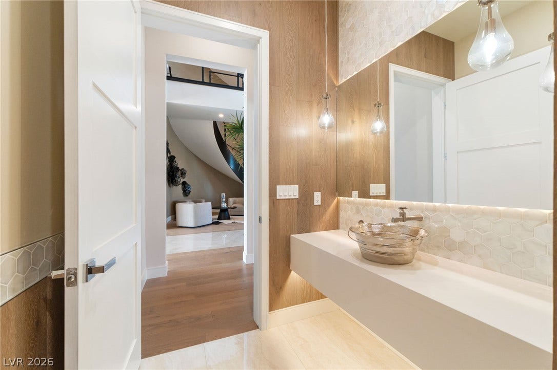 A modern vanity floats against a textured tile backsplash and wood-paneled wall accent.