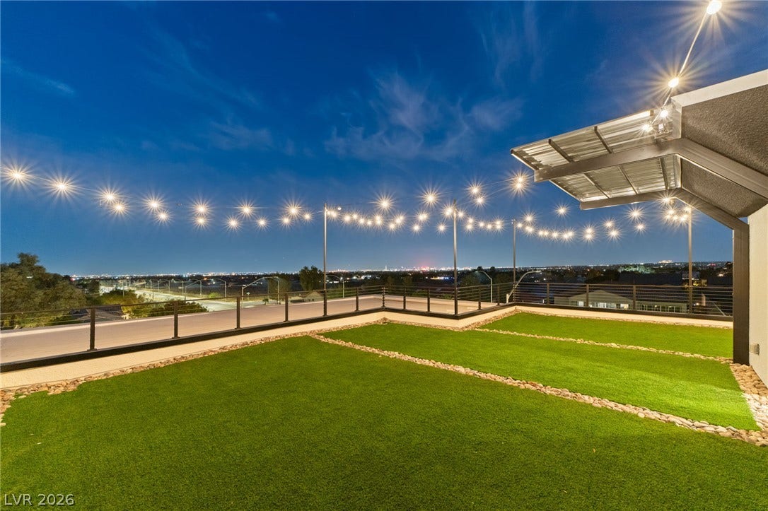 An expansive rooftop terrace delivers sweeping panoramic city light views under the evening sky.