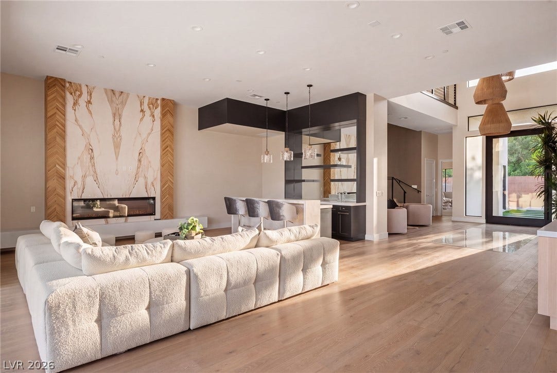 A striking floor-to-ceiling fireplace and sleek wet bar anchor the light-filled main living area.