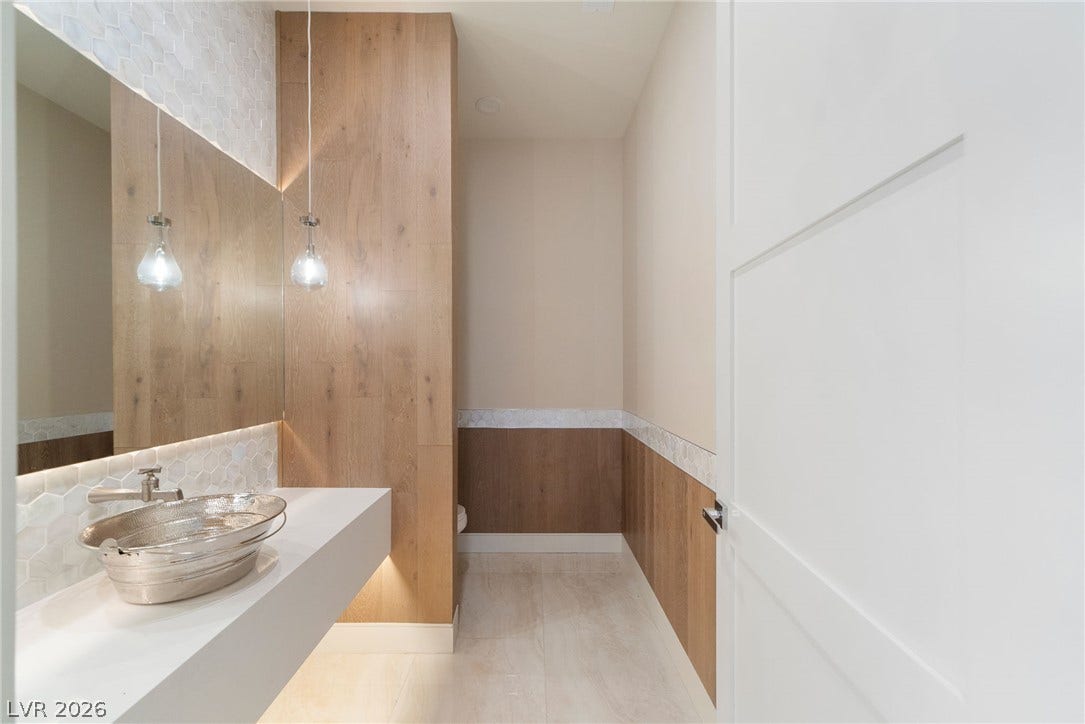 Rich wood paneling and stone tile accents elevate this modern powder room design.