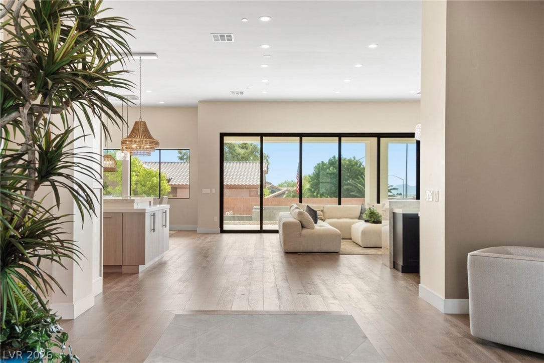Smooth wood floors flow seamlessly through this open layout toward large glass sliding doors.