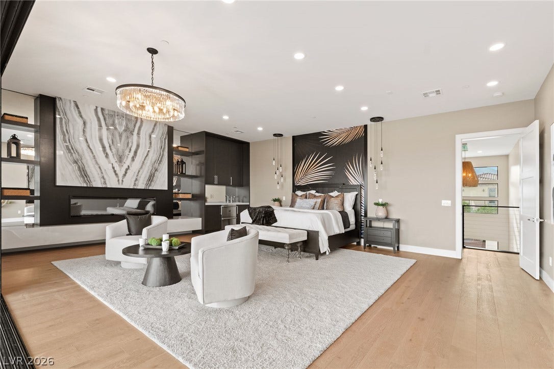 Warm hardwood flooring and a sleek linear fireplace anchor this expansive primary suite.