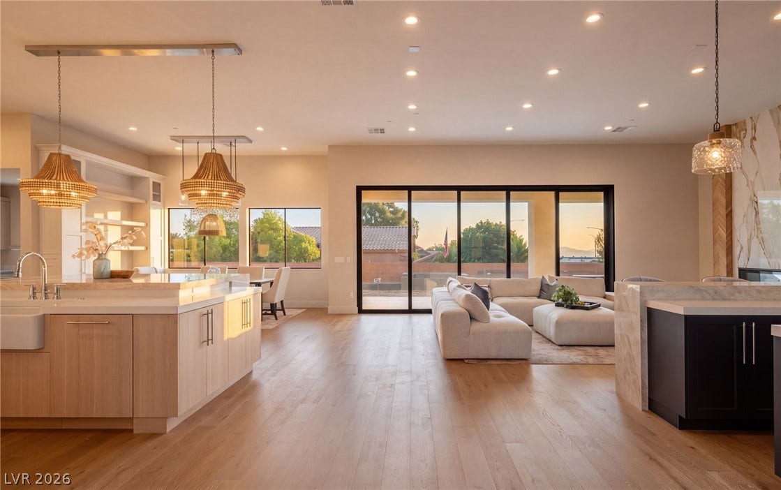 Golden light streams across an expansive open layout highlighted by wide-plank wood flooring.