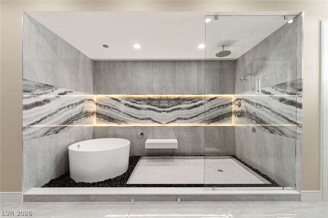 A modern walk-in shower and freestanding soaking tub sit integrated behind seamless glass panels.