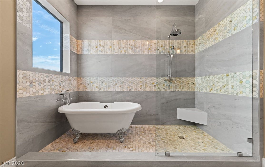 Floor-to-ceiling tile work surrounds a clawfoot soaking tub and glass-enclosed walk-in shower.