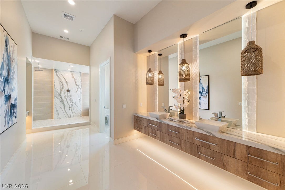 Polished tile flooring and custom wood cabinetry anchor this elegant master bathroom retreat.