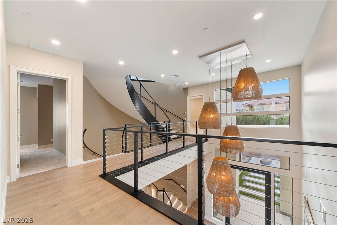 Clean lines and a modern curved staircase define this open, light-filled upper hallway.