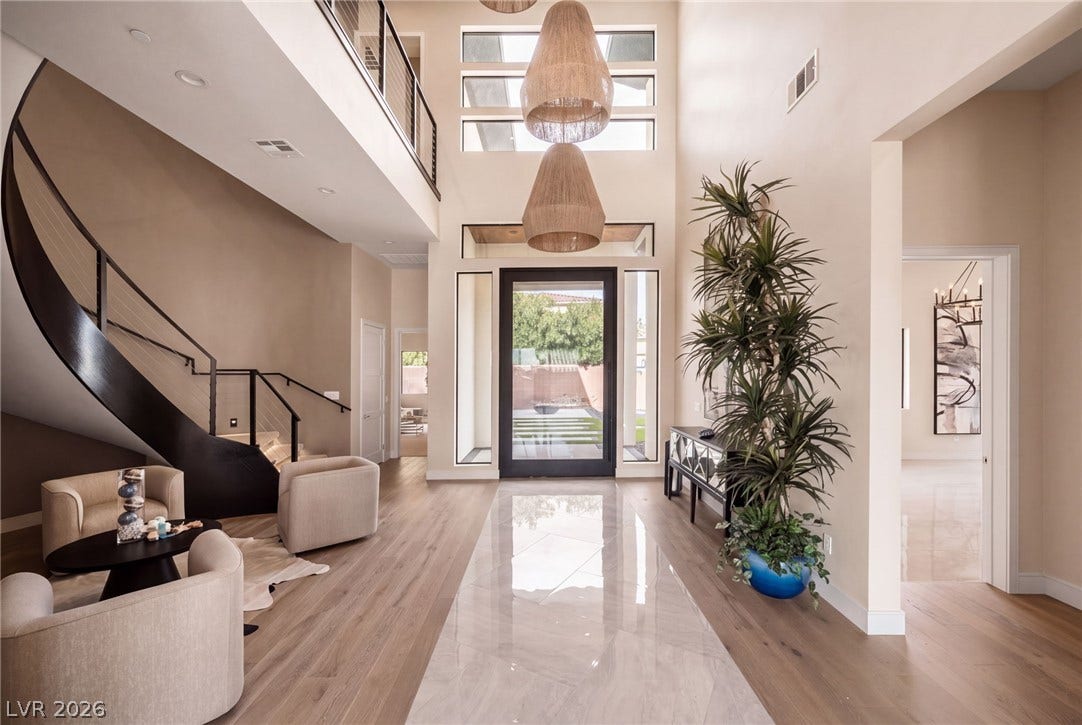Soaring ceilings and a striking curved staircase frame this majestic two-story entry hall.