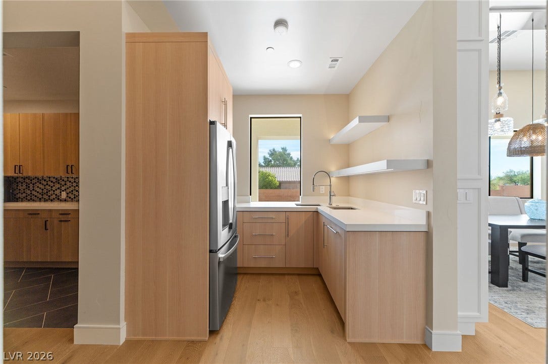 Smooth wood flooring and minimalist floating shelves frame this bright butler pantry area.