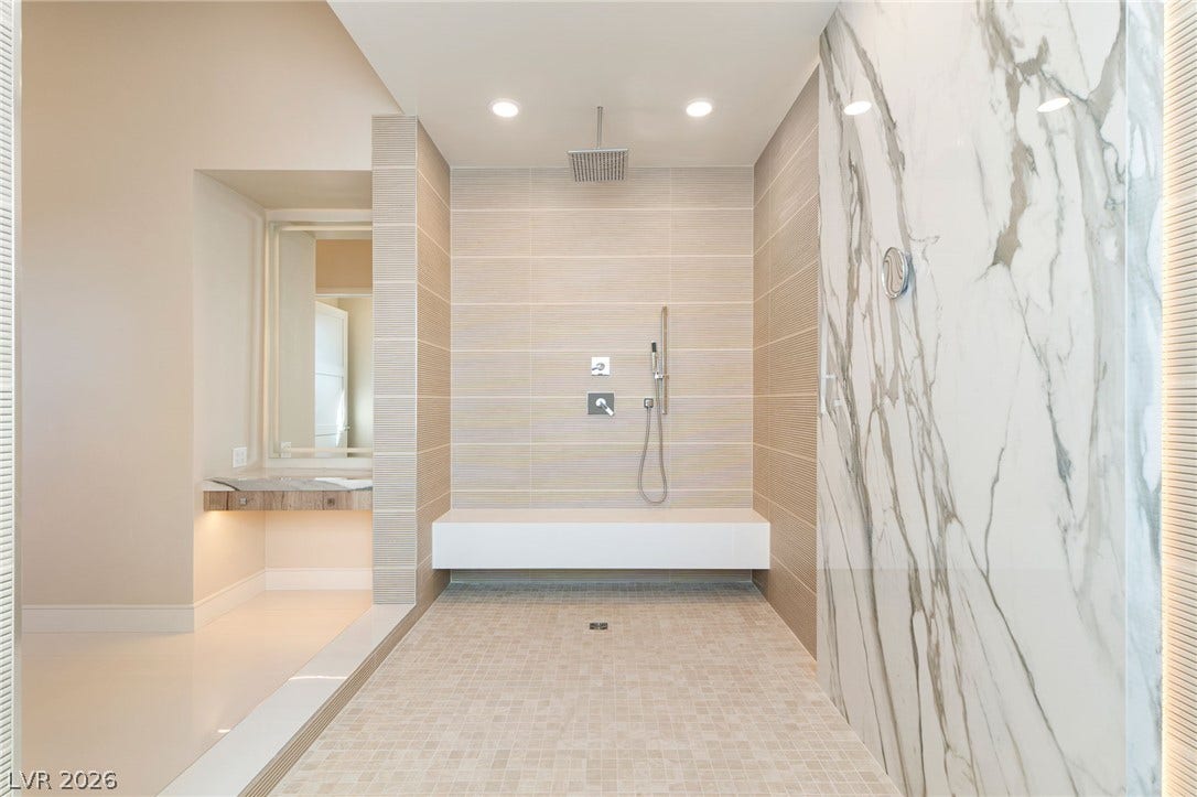 An open walk-in shower highlights this bathroom with tiled walls and a floating bench.