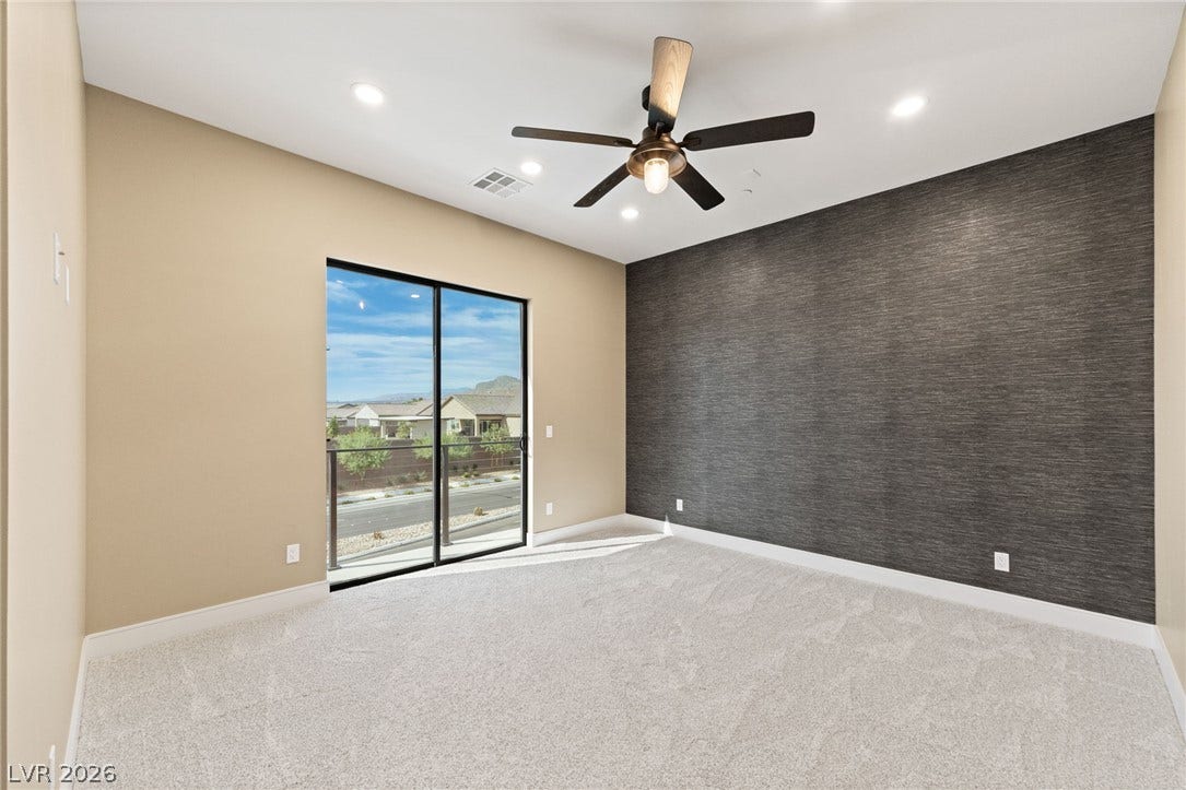 A sliding glass door opens to neighborhood views from this carpeted bedroom.