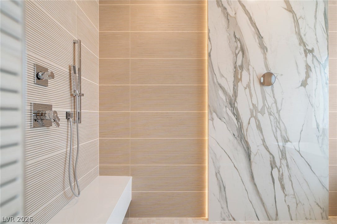 Exquisite marble slabs and textured wall details elevate this walk-in shower design.