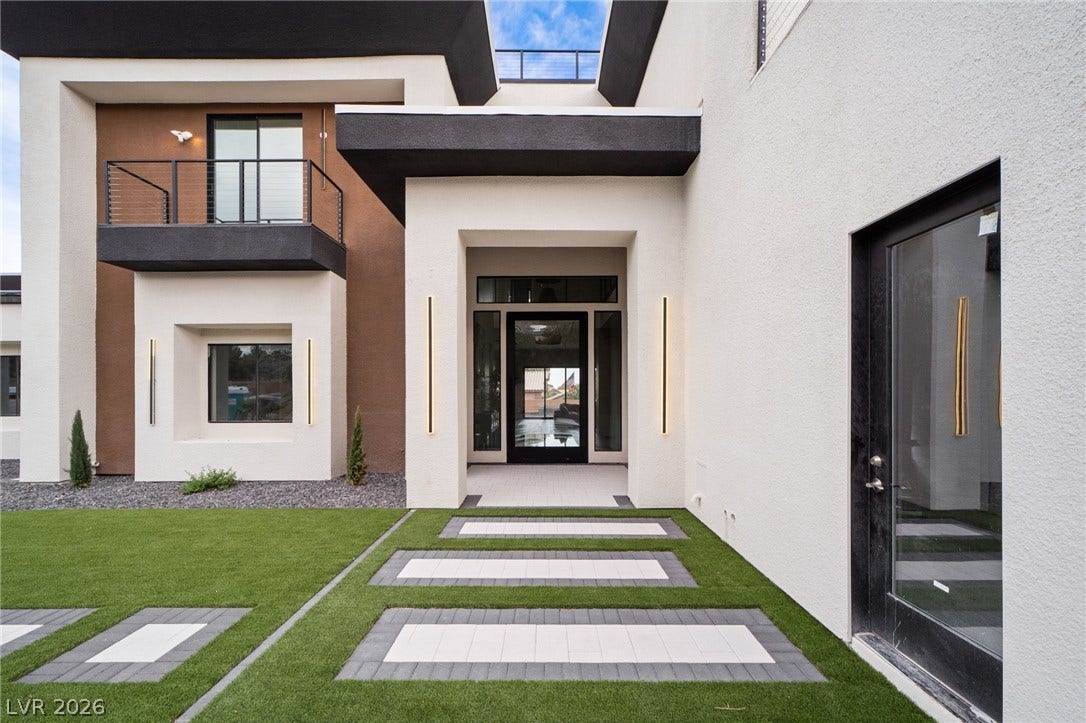 Modern architectural lines define a striking entryway with geometric paver details and clean stucco finishes.
