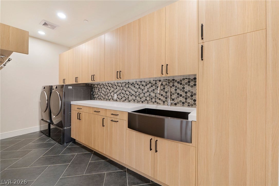 Streamlined cabinetry and a deep apron sink define this highly functional utility space.
