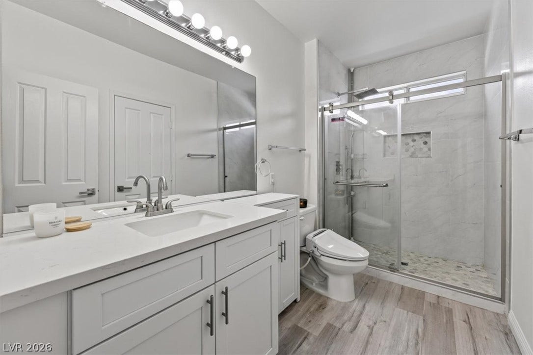 2900 Sunridge Heights Parkway, #1022, Henderson, NV 89052 A contemporary bathroom features a stone-topped vanity and a glass-enclosed walk-in shower.