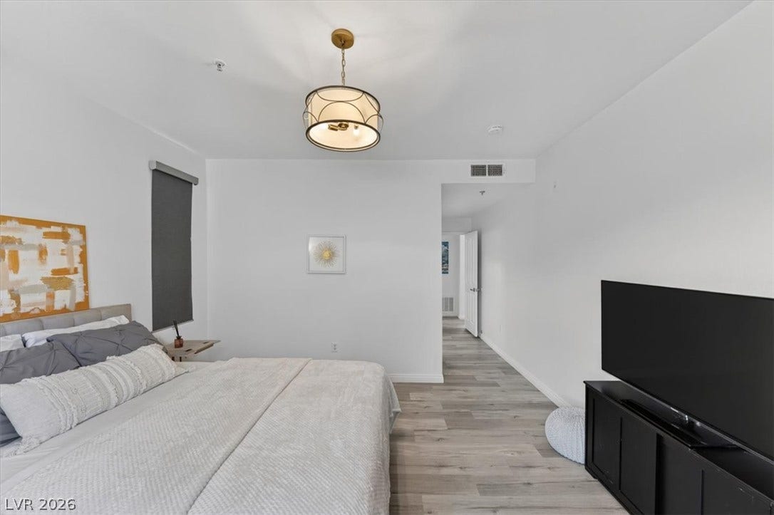 2900 Sunridge Heights Parkway, #1022, Henderson, NV 89052 A spacious bedroom features modern wood-style flooring and a stylish overhead light fixture.