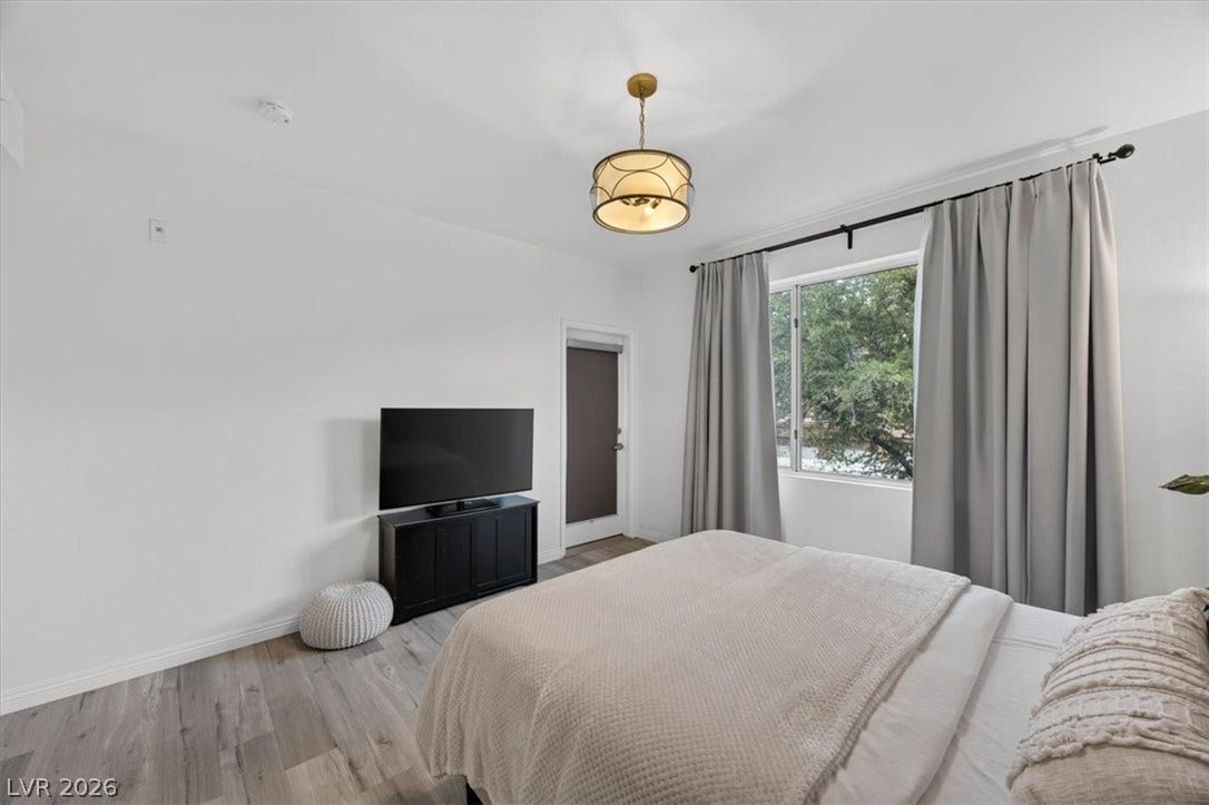 2900 Sunridge Heights Parkway, #1022, Henderson, NV 89052 Smooth wood floors and a large window framing leafy green views elevate this restful bedroom.