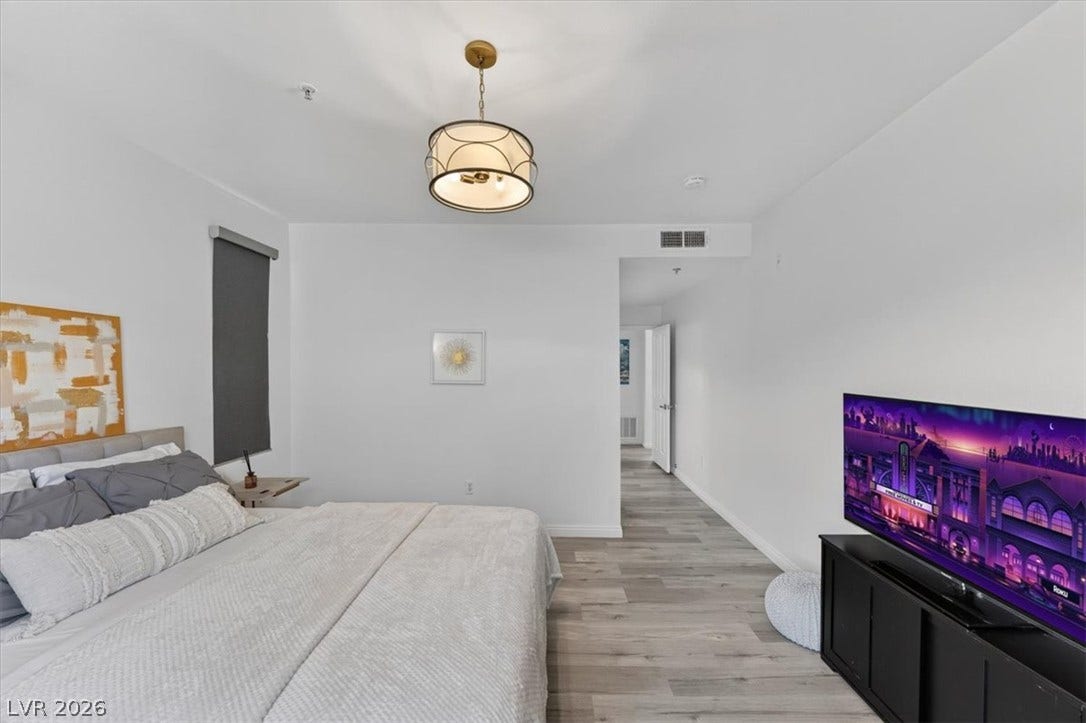 2900 Sunridge Heights Parkway, #1022, Henderson, NV 89052 Smooth wood-style flooring runs throughout this serene bedroom space with clean white walls.
