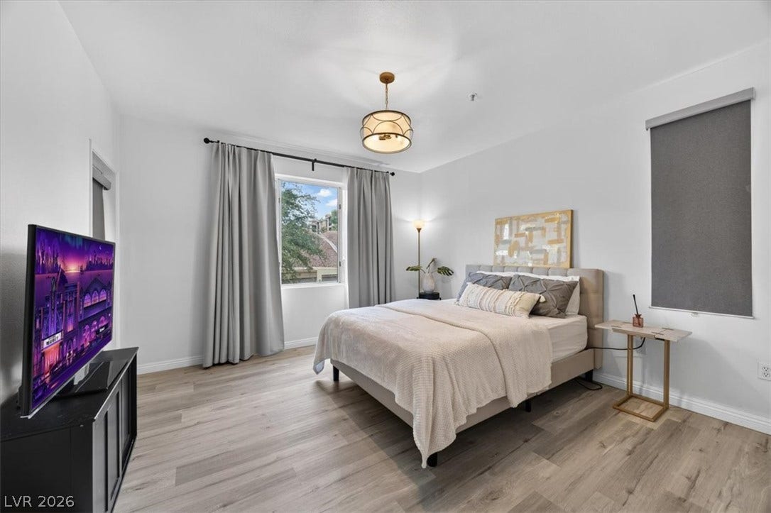 2900 Sunridge Heights Parkway, #1022, Henderson, NV 89052 Smooth wood floors anchor this serene bedroom framed by neutral walls and classic windows.