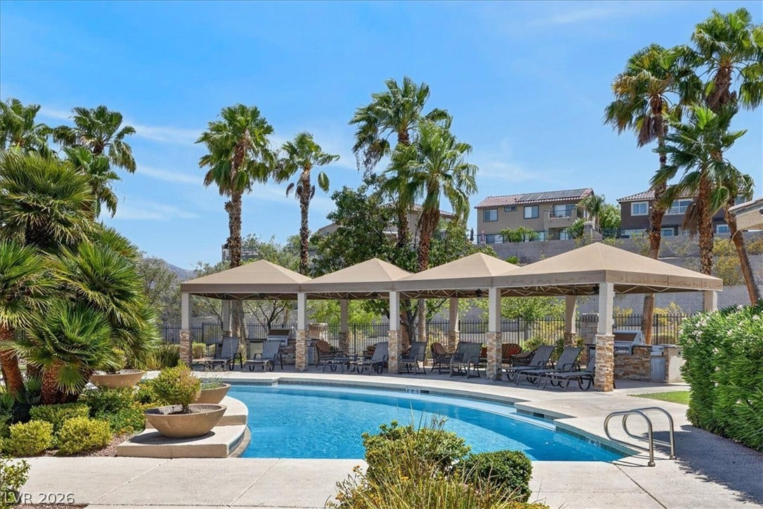 2900 Sunridge Heights Parkway, #1022, Henderson, NV 89052 A sparkling resort-style swimming pool is surrounded by shaded cabanas and towering palm trees.