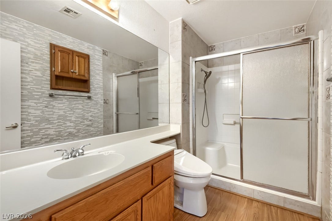 749 Tenderfoot Circle, Henderson, NV 89014 A classic bathroom includes a wooden vanity and a tiled walk-in shower with sliding doors.
