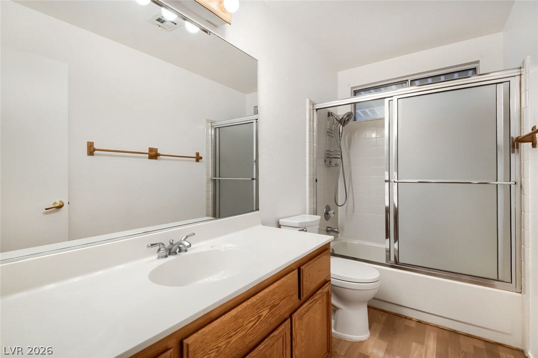 749 Tenderfoot Circle, Henderson, NV 89014 Functional bathroom featuring a wood vanity and a tub shower combo with sliding glass doors.