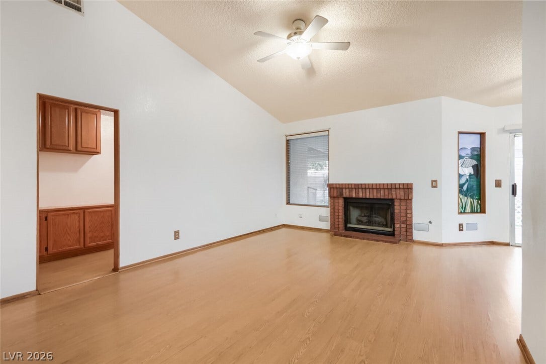 749 Tenderfoot Circle, Henderson, NV 89014 Warm wood flooring and a classic brick fireplace anchor this vaulted living space.