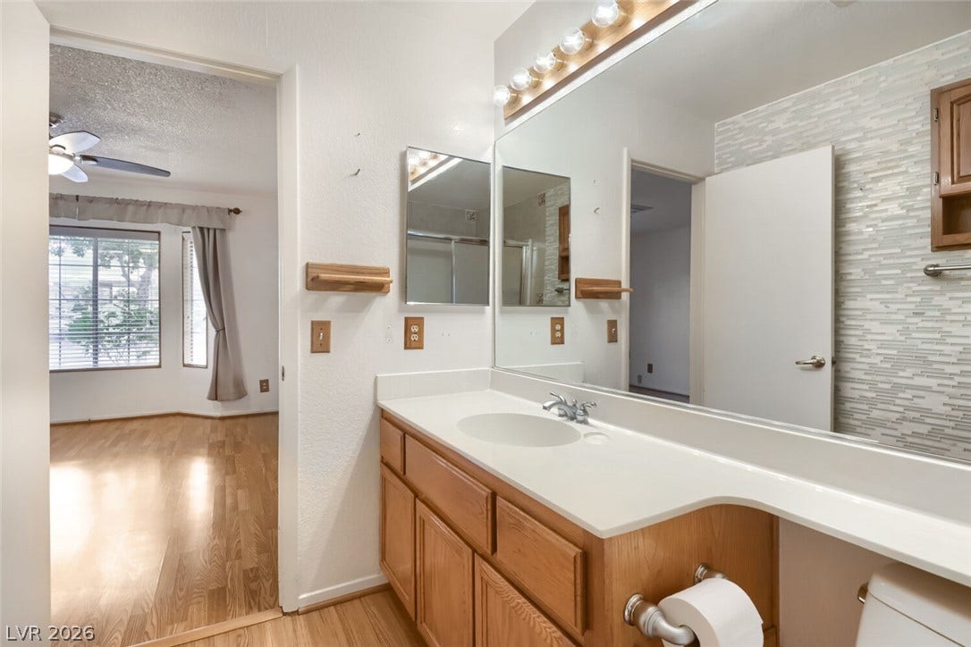 749 Tenderfoot Circle, Henderson, NV 89014 An expansive vanity mirror complements wood cabinetry and clean countertops in this well-appointed bathroom.