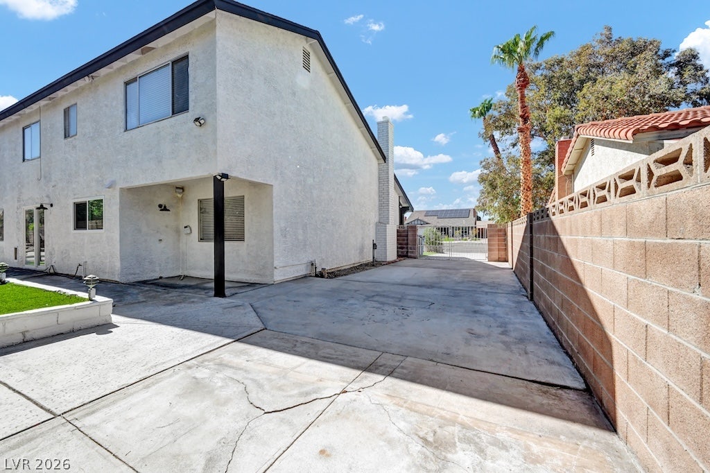 314 Encima Court, Henderson, NV 89014 Concrete paving extends alongside the textured stucco exterior, bordered by a solid block wall.