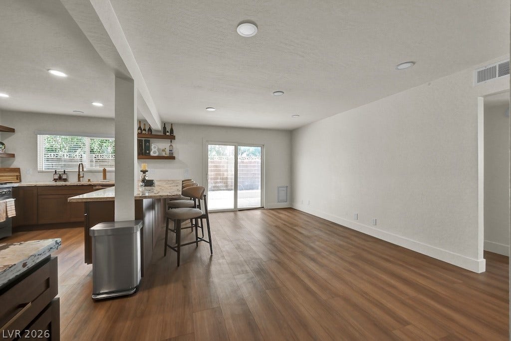 314 Encima Court, Henderson, NV 89014 Rich wood-look flooring anchors a spacious layout connecting seamlessly to the backyard through glass doors.