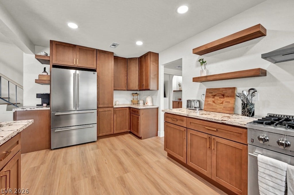314 Encima Court, Henderson, NV 89014 Rich wood cabinetry and stone countertops anchor this functional cooking space with open shelving.