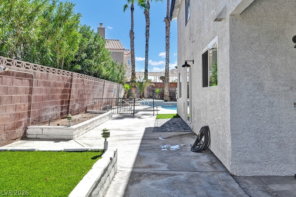 314 Encima Court, Henderson, NV 89014 A spacious concrete side yard features raised garden beds and leads toward the pool area.